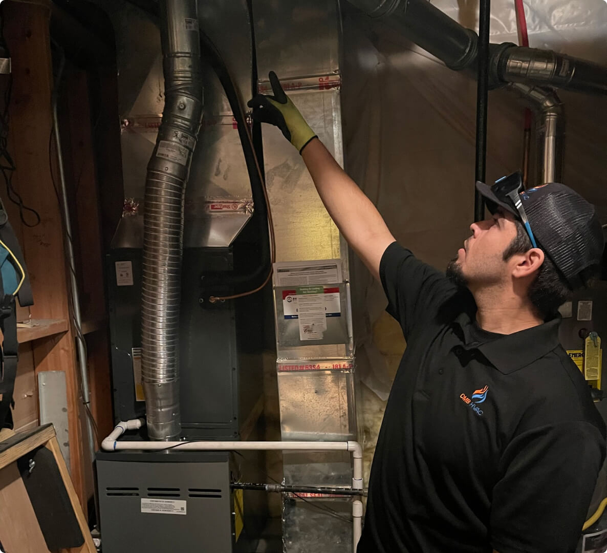 Technician inspecting HVAC system in a basement.