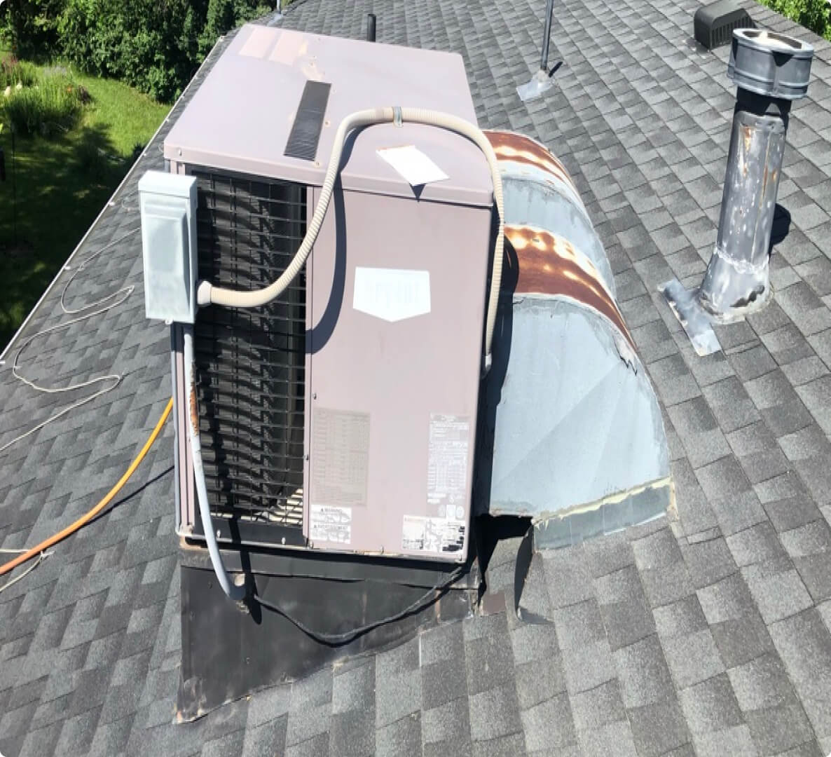 HVAC unit on residential shingled rooftop in daylight.