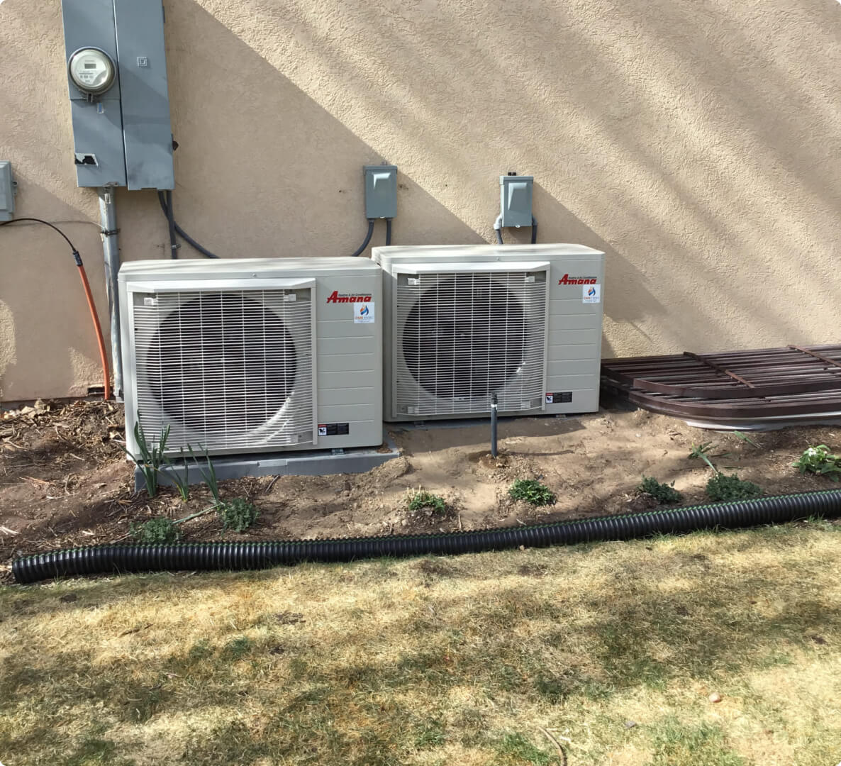 Two Amana air conditioning units outside a residential home.