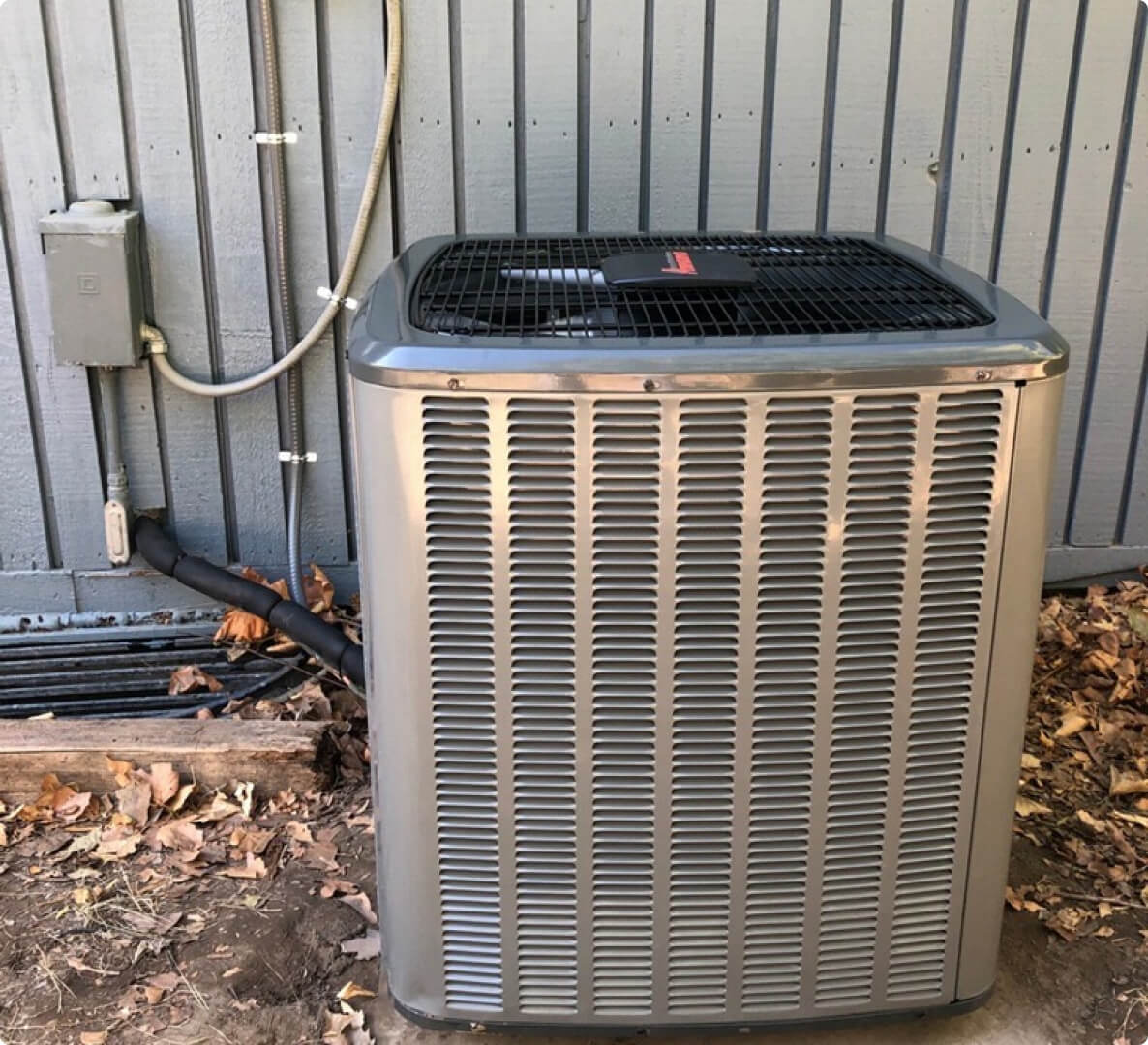Outdoor central air conditioning unit beside house.